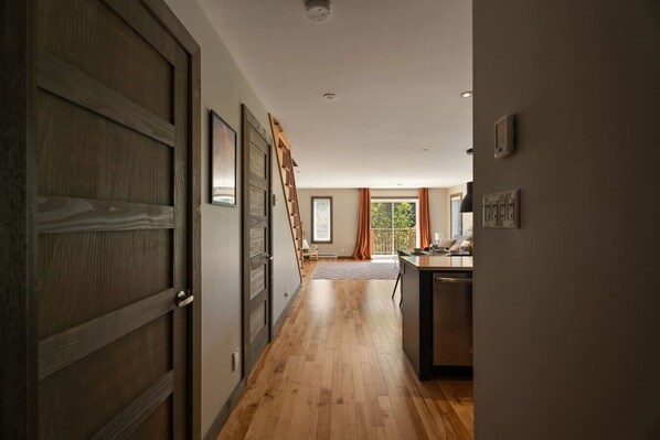 A hallway leading to a dining area with a wooden floor, a staircase, and a view of the outdoors.