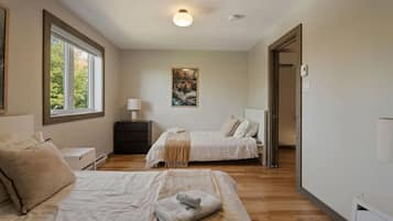 A bedroom with two beds, a nightstand, a lamp, and a painting on the wall.