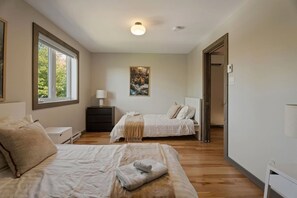 A bedroom with two beds, a nightstand, a lamp, and a painting on the wall.