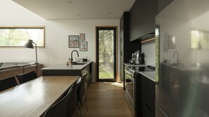 Eine moderne Küche mit einer zentralen Kochinsel, einem eingebauten Backofen und einem großen Fenster mit Blick auf Grünflächen.