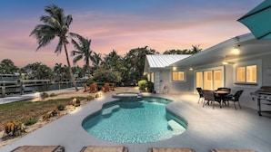A modern house with a swimming pool, outdoor furniture, and a view of the water.