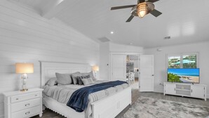 A bedroom with a bed, bedside tables, a ceiling fan, and a TV.