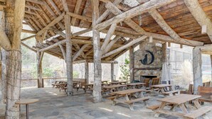 Un pabellón rústico al aire libre con suelo de piedra y bancos de madera.