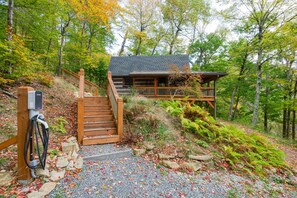 A cabin with a wooden staircase leading to a deck, surrounded by trees and a gravel path. - Le Nest Wolf Laurel cabin + Hatley Point Ski (Madison County)