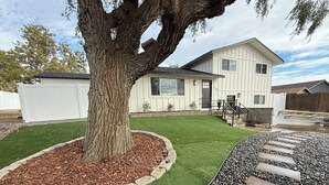 A residential property with a well-maintained lawn, a large tree, and a stone pathway leading to the house. - Modern Upscale Hermiston Home • Pet-Friendly • Private Fenced Yard (Hermiston)