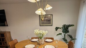 A dining area with a round wooden table, brown chairs, and a vase of white flowers. - Modern Upscale Hermiston Home • Pet-Friendly • Private Fenced Yard (Hermiston)