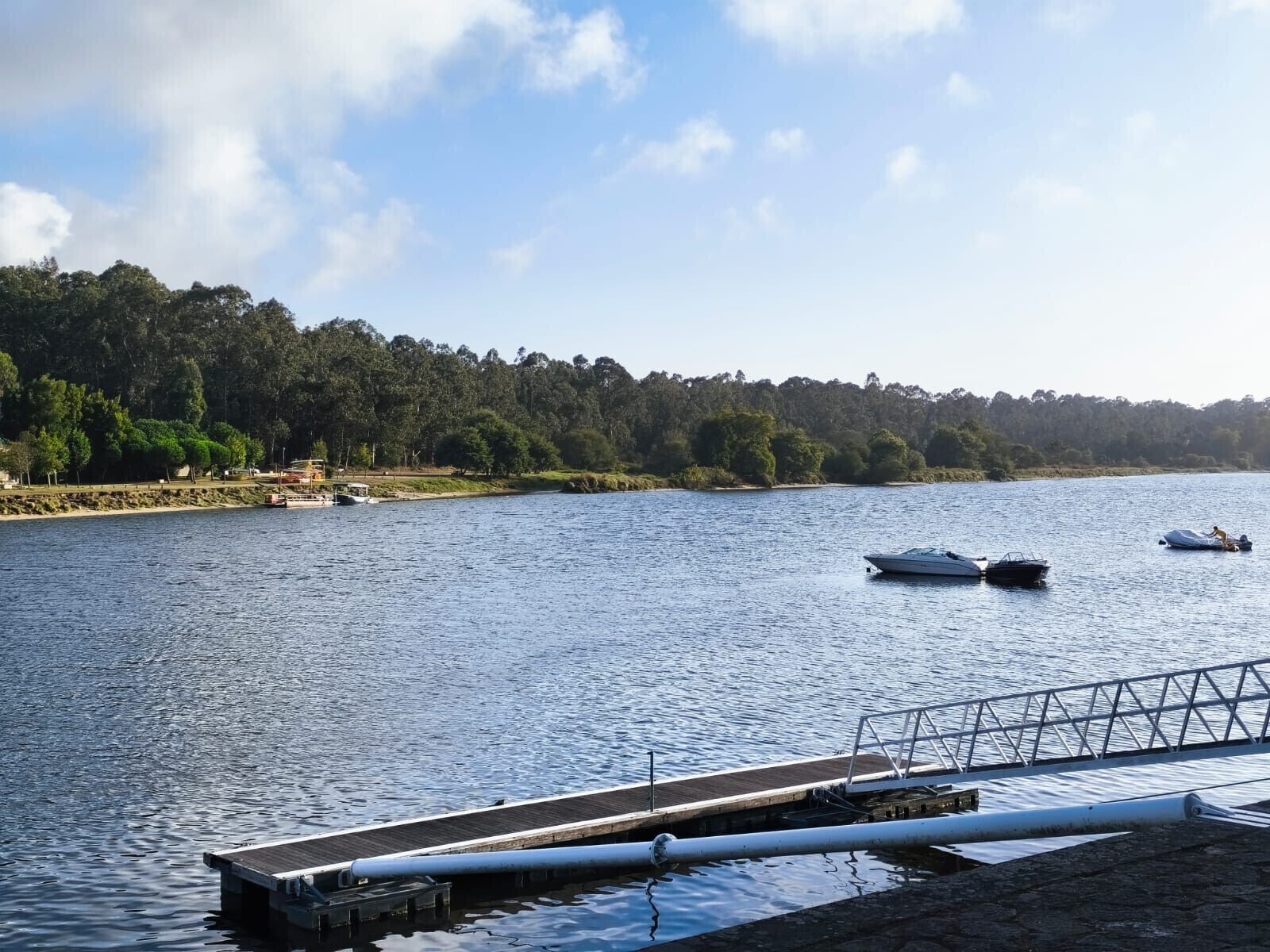 A calm lake with boats, a dock, and a forested shoreline.