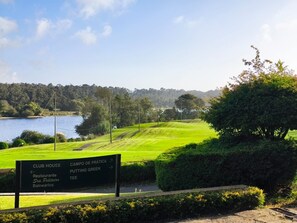 A sign with directions to the club house, campo de prática, putting green, and tee.