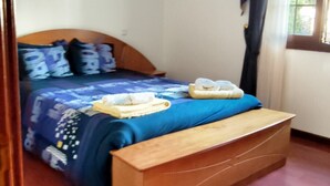 Une chambre à coucher avec un lit, une tête de lit en bois et une fenêtre avec des rideaux.