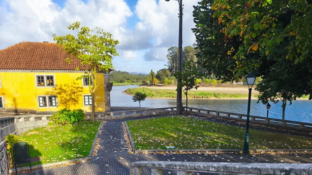Un bâtiment jaune avec un toit en tuiles, un chemin pavé et un escalier en pierre menant vers le bas.
