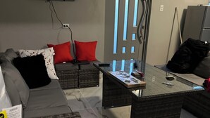 A living room with a sofa, a coffee table, and a television mounted on the wall.
