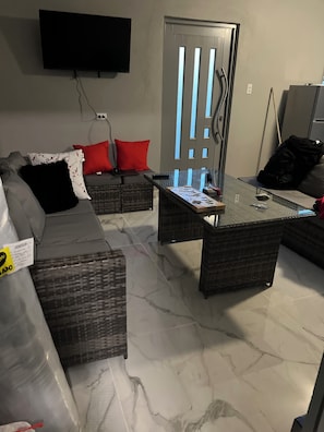 A living room with a sofa, a coffee table, and a television mounted on the wall. - Delightful 3-bedroom house with AC in charming Rincón (Rincón)