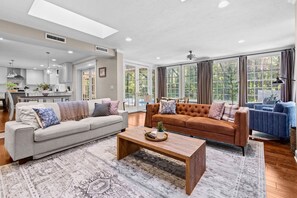 A spacious living room with a grey sofa, a brown sofa, and a blue armchair, a wooden coffee table, and a patterned rug. - 4/3 with pool NW Gainesville (Gainesville)