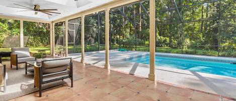 Ein überdachter Außenbereich mit Pool, Sitzgelegenheiten und Deckenventilator.