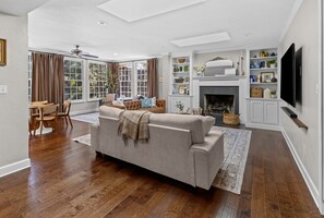 Una sala de estar amplia con un sofá, una chimenea, un televisor y un comedor con mesa y sillas.
