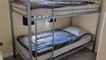 Ein Stockbett mit zwei Etagen, ein Fenster mit Vorhängen und ein Teppichboden.