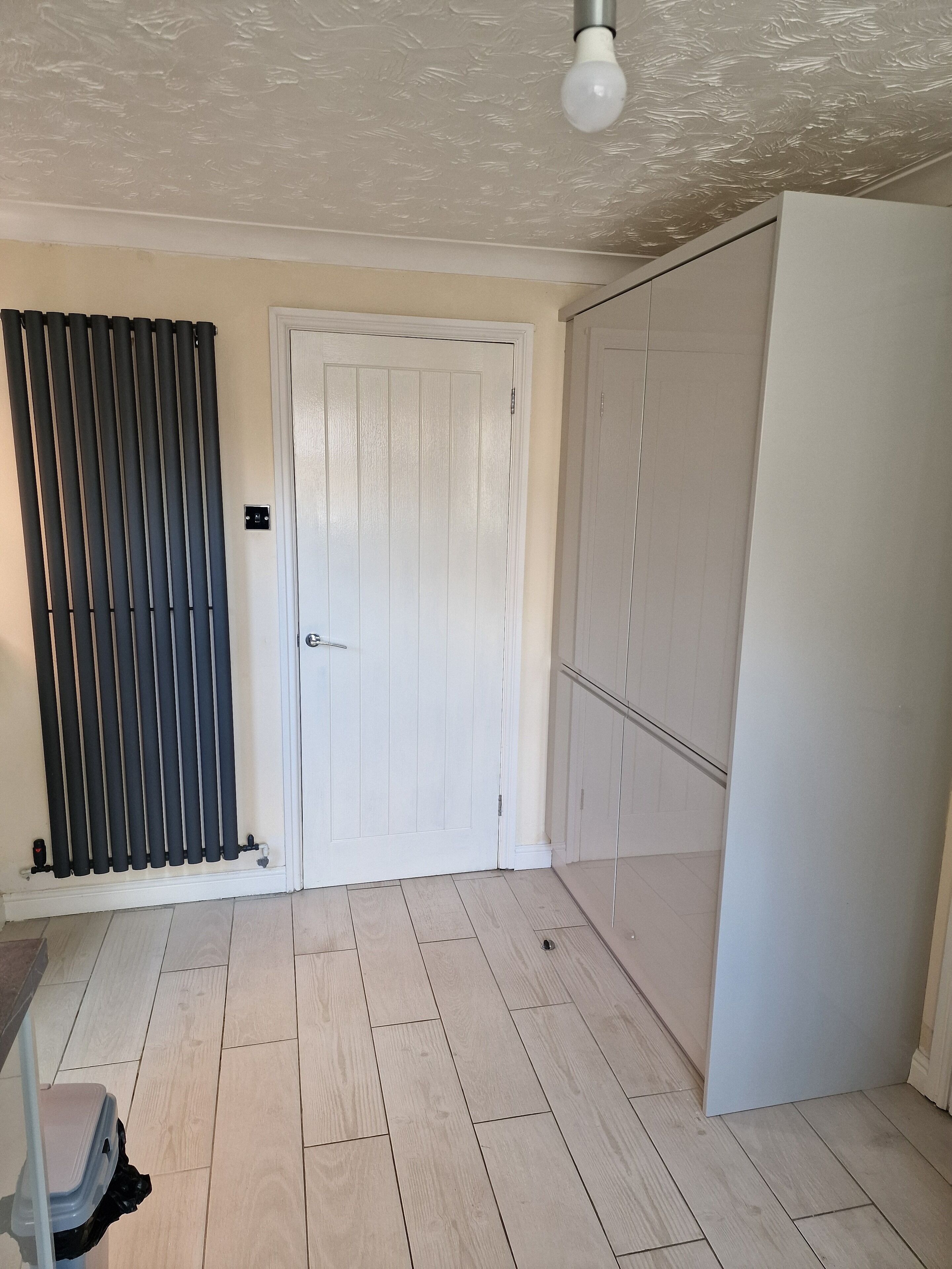 A room with a white door, a radiator, and a wardrobe.