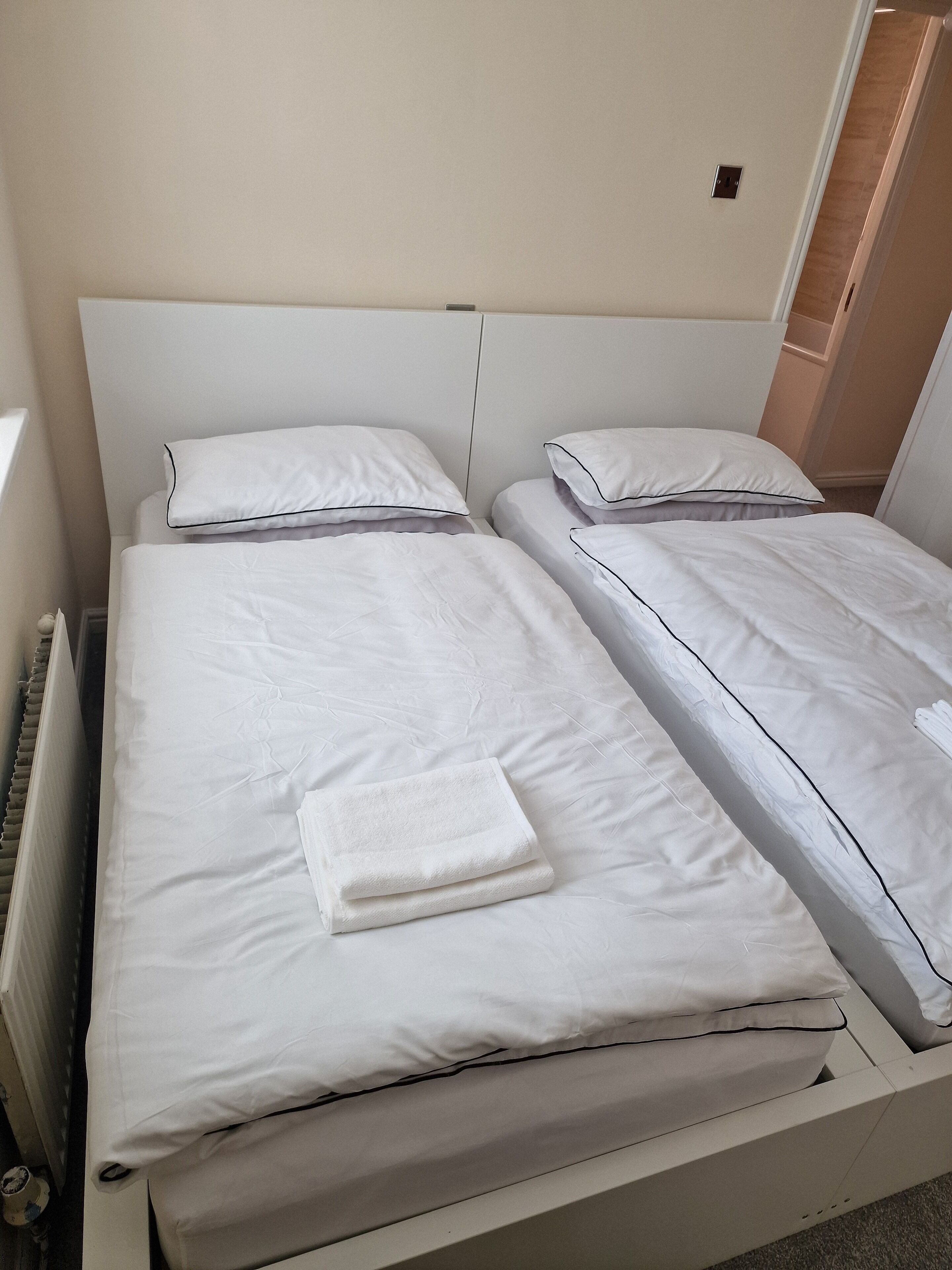 Un lit simple avec une literie blanche et une serviette blanche pliée.