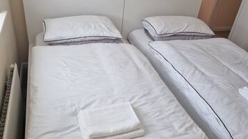 Un lit simple avec une literie blanche et une serviette blanche pliée.