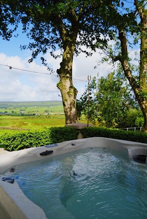 Ein Whirlpool mit Blick auf eine grüne Landschaft und Bäume.
