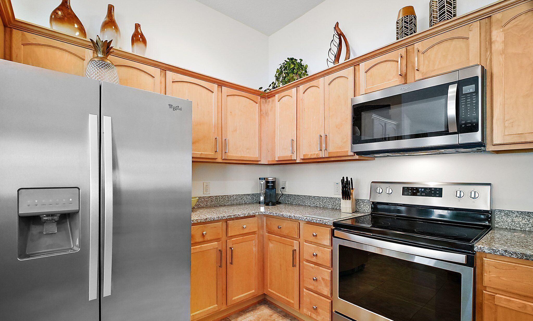 Una cucina con mobili in legno, un frigorifero in acciaio inox, un forno a microonde e un forno.