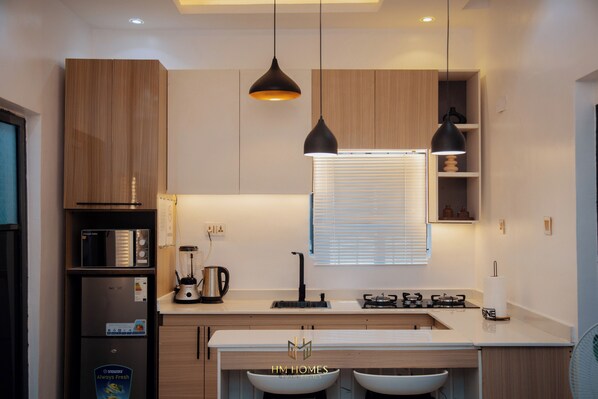 A modern kitchen with wooden cabinets, a built-in oven, a sink, and two pendant lights.
