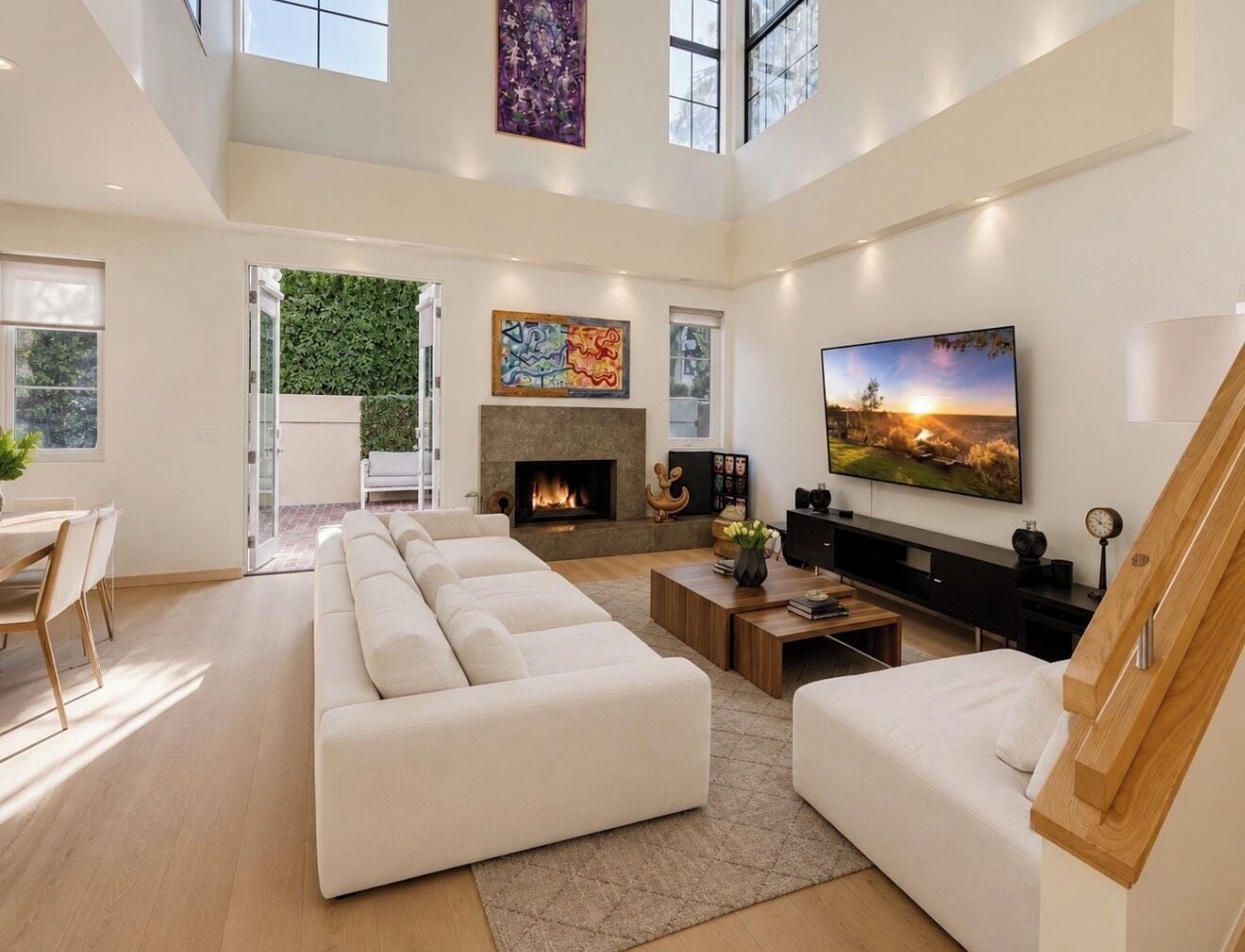 A spacious living room with a fireplace, a large TV, and a staircase.