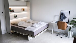 A modern bedroom with a bed, a desk, and a chair. - New modern apartment, 74sqm, balcony, king-size box-spring bed (Offenburg)