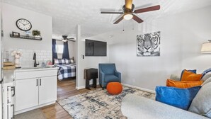 Un salon moderne avec un canapé, un fauteuil bleu, un tapis et une œuvre d’art représentant un tigre accrochée au mur.