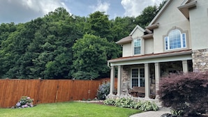 A two-story house with a stone facade, a covered porch, and a well-maintained lawn.