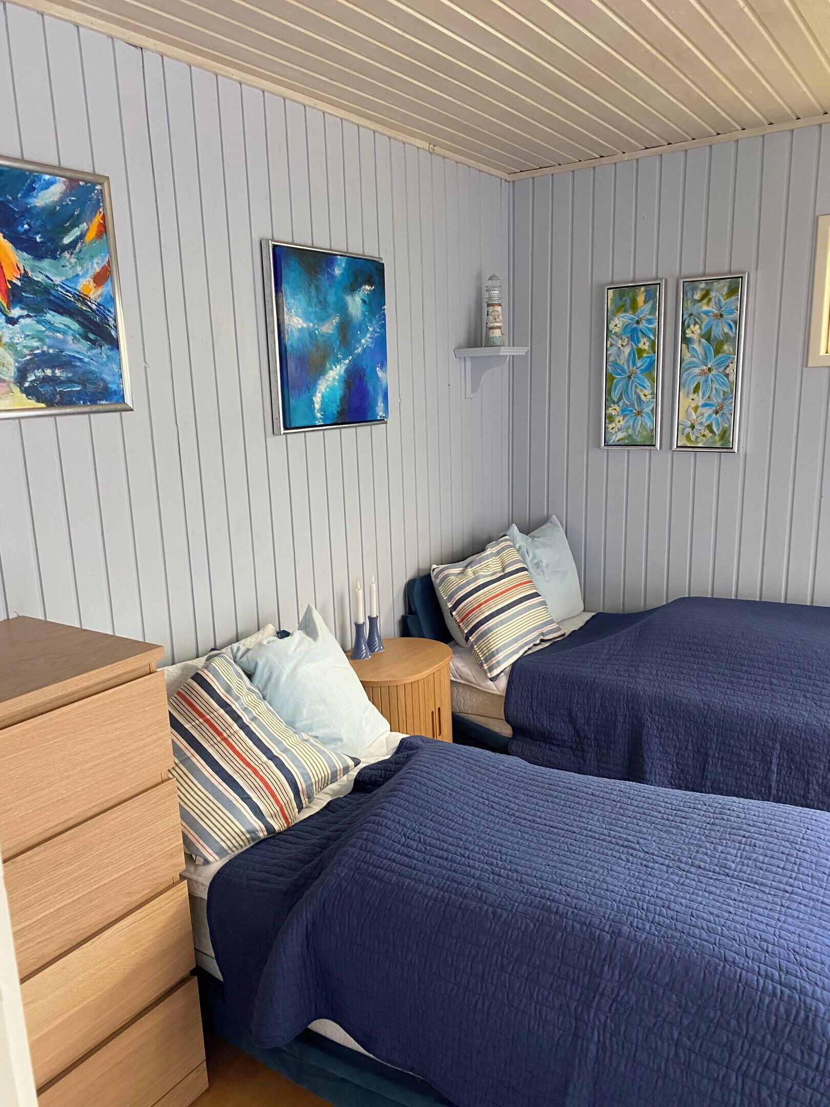 Un dormitorio con dos camas, un aparador y cuadros colgados en la pared.