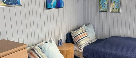 Un dormitorio con dos camas, un aparador y cuadros colgados en la pared.