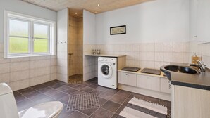 A modern kitchen with a built-in washing machine, a sink, and a window. - Peaceful cottage in scenic surroundings (Tarm)