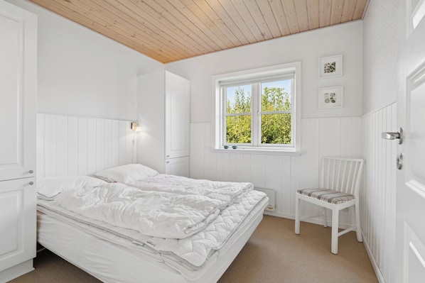 Une chambre Ă coucher avec un lit, une fenĂȘtre, une chaise et une Ă©tagĂšre fixĂ©e au mur.