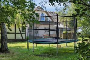 A trampoline in a backyard with a house in the background.