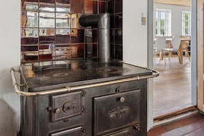A vintage stove with a metal handle, a glass door with a metal latch, and a tiled backsplash.