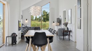 A modern dining area with a long table, black chairs, and a unique ceiling light.