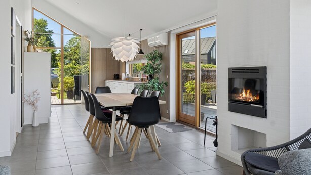 A modern kitchen with a dining area, a fireplace, and a view of the outdoors.