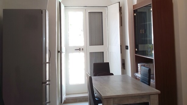 Eine moderne Küche mit Essbereich, ausgestattet mit einem großen Tisch, Stühlen, einem Kühlschrank und einem Fernseher.
