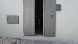 Eine Tür mit der Aufschrift '5' darüber, ein kleines Fenster mit einer Metallplatte und ein an der Wand montiertes Stromdosenkast.