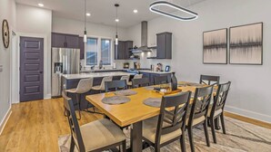 Una cocina moderna con una isla central, armarios oscuros e iluminación colgante.