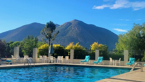 A swimming pool with lounge chairs and a mountain backdrop. - Mountain View Retreat ~Deck +grill! ~Jacuzzi Tub! (Flagstaff)