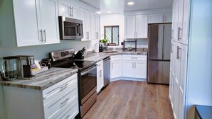 A modern kitchen with white cabinets, stainless steel appliances, and a marble countertop. - Mountain View Retreat ~Deck +grill! ~Jacuzzi Tub! (Flagstaff)