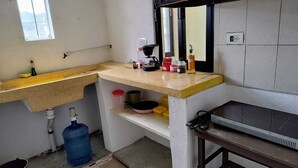 A kitchen with a countertop, a sink, a water dispenser, and a large blue water container. - Comfortable and cozy apartment (Oaxaca de Juárez)