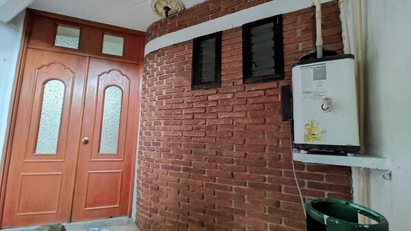 A brick wall with a white electrical box and a green bucket.