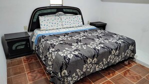 A neatly made bed with a floral bedspread and matching pillows, flanked by two bedside tables with lamps. - Comfortable and cozy apartment (Oaxaca de Juárez)