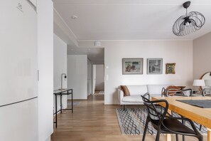 Un salon moderne avec un canapé, une table à manger, des chaises et des œuvres d’art accrochées au mur.