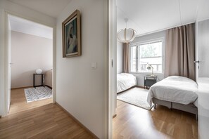 A modern bedroom with a large bed, a bedside table, a lamp, and a window with curtains.