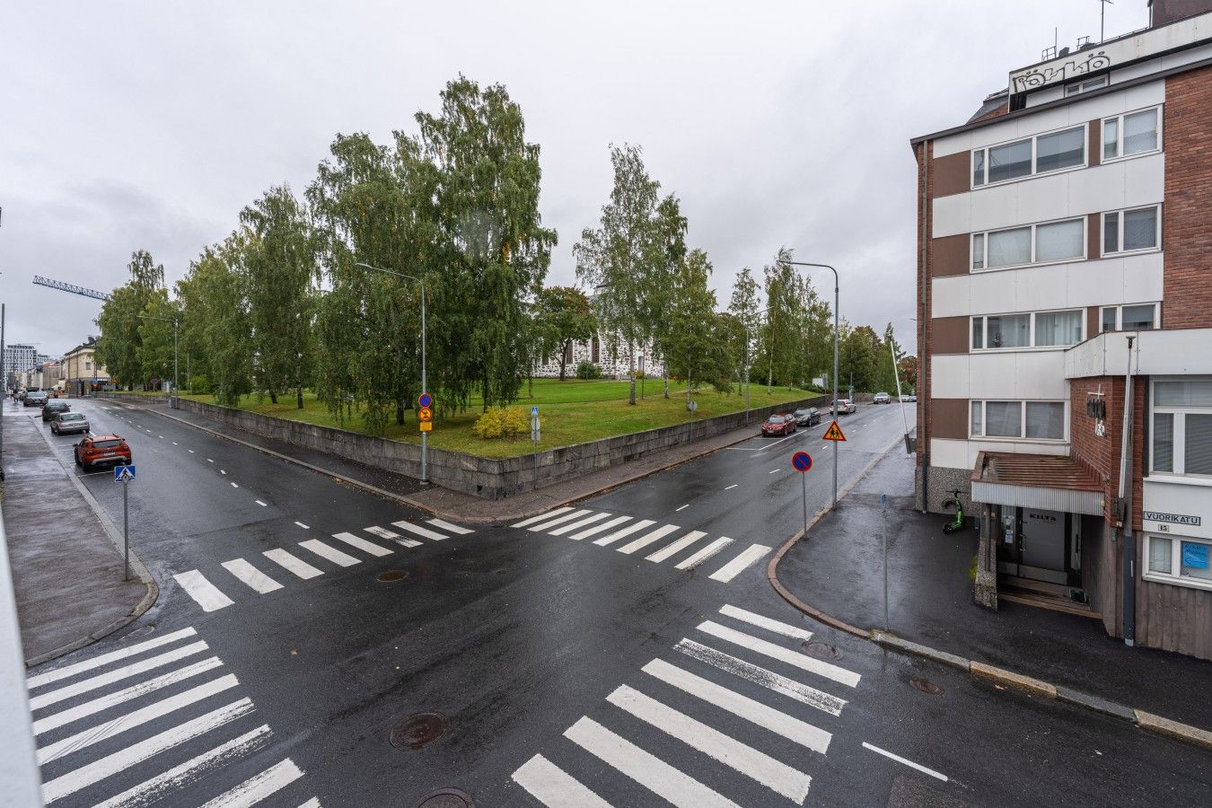 Useita ajokaistoja sisältävä tie, jossa on jalankulkijoiden suojatiet, liikenneympyrä ja rakennus, jossa on kyltti, jossa lukee ”VVRIKATU”.