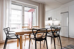 A modern kitchen with white cabinets, a microwave, and a refrigerator. - High Quality 2BR Home with Sauna in Downtown (Kuopio)
